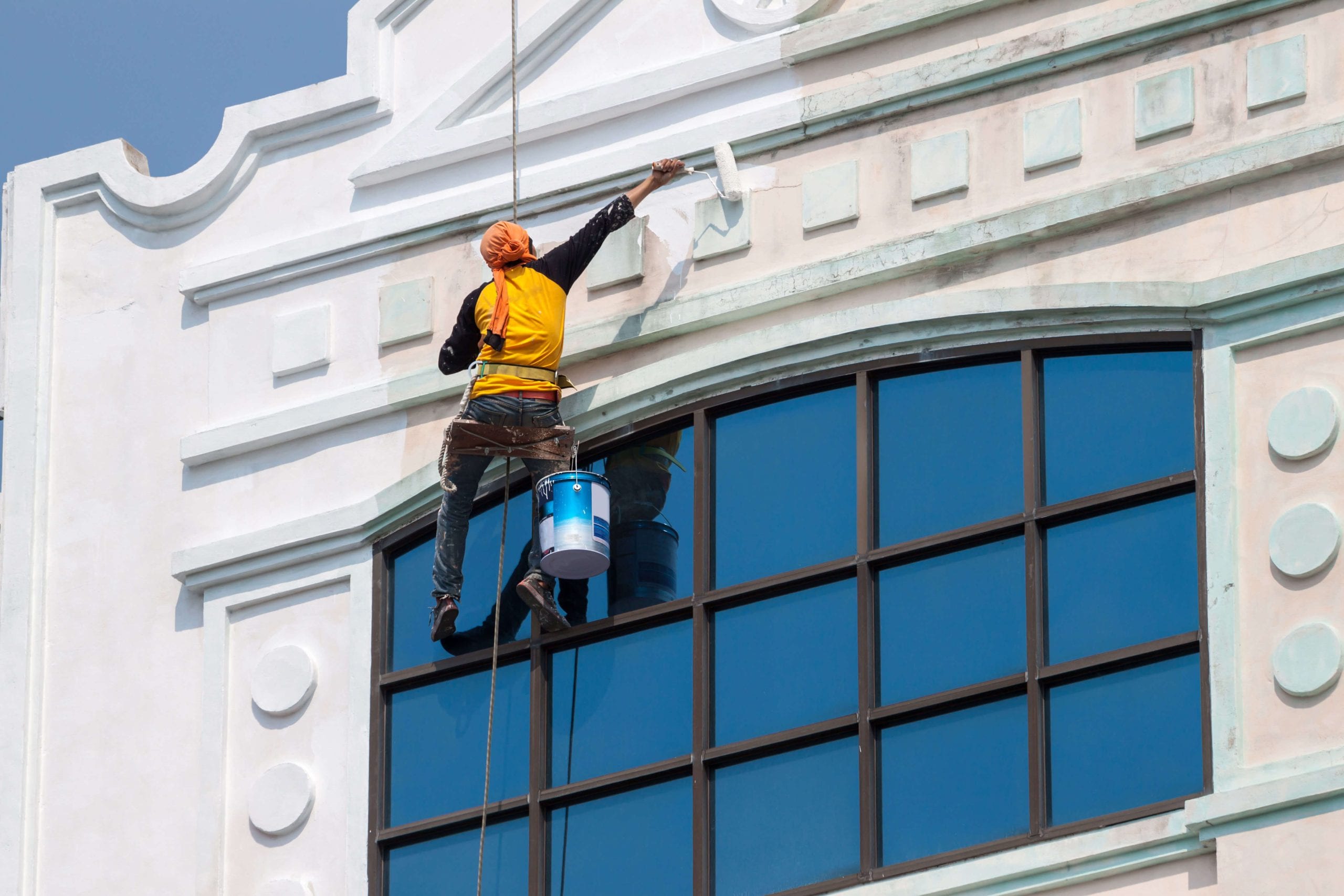 A team of professional painters working on the exterior of a commercial building in Albuquerque, applying fresh coats of paint to revitalize its appearance.